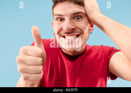 J'ai gagné. Large succès happy man celebrating être un gagnant. Image dynamique de l'homme de race blanche sur fond bleu modèle studio. La victoire, delight concept. La notion d'émotions faciales. Couleurs tendance Banque D'Images