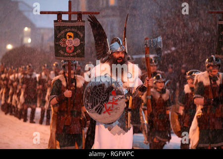 Guizer Jarl John Nicolson et son équipe mars à Lerwick, comme de la neige tombe sur l'Îles Shetland au cours de l'Up Helly Aa festival viking. Originaires dans les années 1880, le festival célèbre le patrimoine scandinave Shetland. Banque D'Images