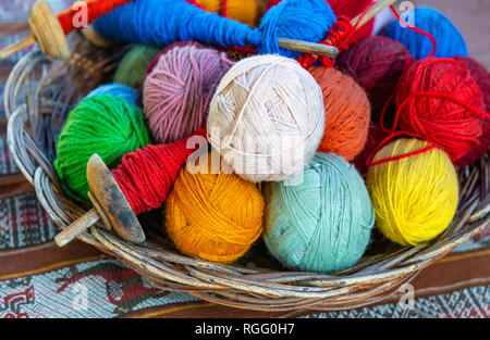 Panier avec fil de laine Alpaga colorés ballons et spinning axes dans un centre de production textile dans Cusco, Pérou. Banque D'Images