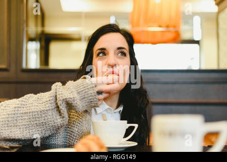 Femme d'âge moyen, des vraies personnes, manger un croissant avec le café dans un café. Banque D'Images