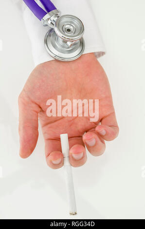 Stéthoscope sur une main tenant une cigarette sur un tableau blanc. Banque D'Images