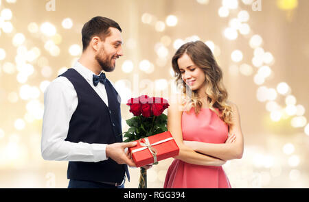 Happy man giving woman fleurs et présent Banque D'Images