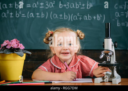 Petite fille à l'école élémentaire classe de sciences, utiliser l'équipement. microscope Lycéenne apprendre à travailler sur du matériel de laboratoire Banque D'Images