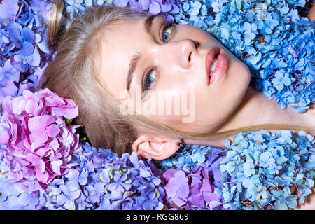 Fashion portrait de femme. La bonne santé des cheveux et de la peau. La beauté de l'été. Printemps femme avec des fleurs d'hortensias. Les produits cosmétiques de maquillage et soins de la jeune fille avec l'été. Banque D'Images