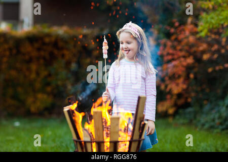 Enfant avec smores au feu de camp. Mini rôti sur la guimauve bâton à feu. Plein air famille d'automne. Camping enfant à l'automne de la forêt. Peu de GI Banque D'Images