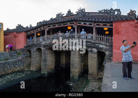 Prendre un touriste avec son smartphone selfies devant le pont couvert japonais aka la pagode Chua Cau dans Hoi An, Vietnam Banque D'Images