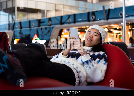 Fille à l'aide de téléphone en attente à l'aéroport gate Banque D'Images