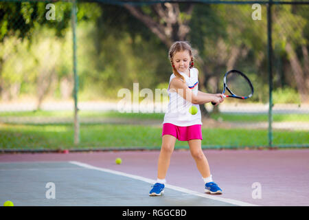 Enfant jouant au tennis sur un court intérieur. Petite fille avec raquette de tennis et la balle dans le sport club. Exercice actif pour les enfants. Activités d'été pour les enfants. Banque D'Images