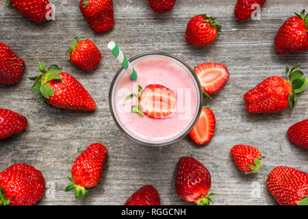Smoothie aux fraises milkshake ou dans un verre avec de la paille avec les baies fraîches sur fond de bois rustique. alimentation saine. Vue de dessus Banque D'Images