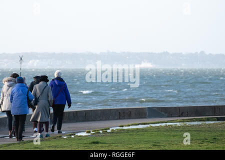 Un groupe de personnes âgées de prendre une promenade de bord de mer sur une très jour venteux Banque D'Images