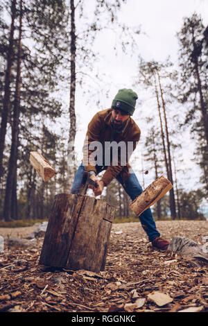 Young man chopping woog dans la forêt Banque D'Images