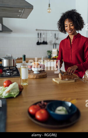 Femme debout dans la cuisine, le pain en tranches Banque D'Images