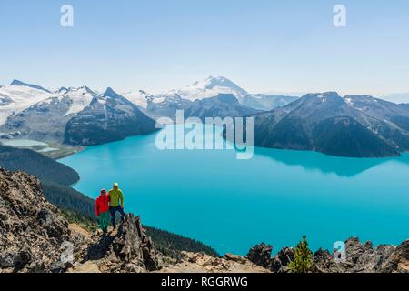 Vue du Panorama Ridge trail, deux randonneurs sur un rocher, Garibaldi Lake, lac glaciaire, Turquoise Mountain Peak et la tromperie de la Garde Banque D'Images