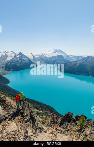 Vue du Panorama Ridge trail, deux randonneurs sur un rocher, Garibaldi Lake, lac glaciaire, Turquoise Mountain Peak et la tromperie de la Garde Banque D'Images