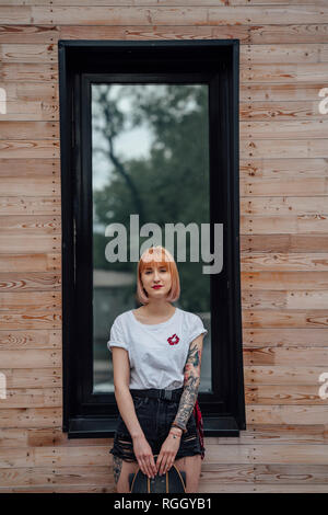 Portrait of young woman standing outside building avec carver skateboard Banque D'Images