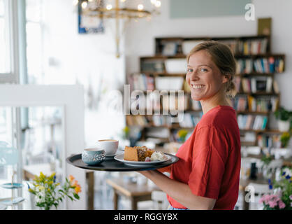 Portrait de jeune femme qui sert du café et des gâteaux dans un café Banque D'Images