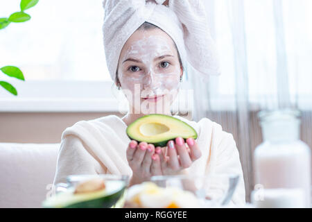 Belle jeune femme heureuse avec un masque d'avocat naturel sur son visage. Concept des soins de la peau et des soins Spa à la maison Banque D'Images