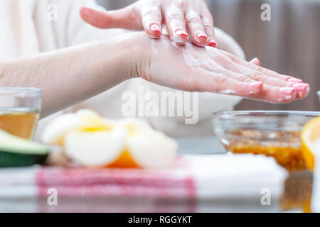 La femme l'application de la crème sur ses mains hydratant et nourrissant avec les cosmétiques naturels close-up. Concept d'hygiène et de soins pour la peau Banque D'Images