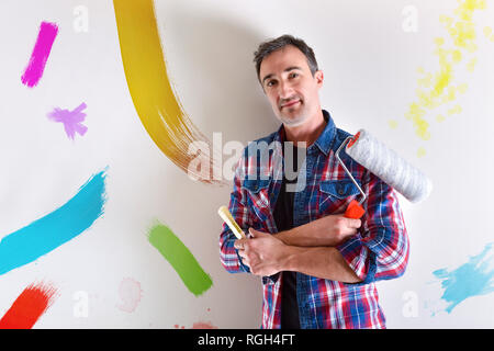 Homme avec les armes et les outils dans les mains avec des échantillons de couleur sur le mur. Vue de face. Composition horizontale. Banque D'Images