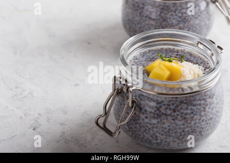 Chia mangue dessert avec lait végétal dans un bocal en verre, végétalien collation ou dessert sur fond gris clair, d'une saine alimentation Banque D'Images