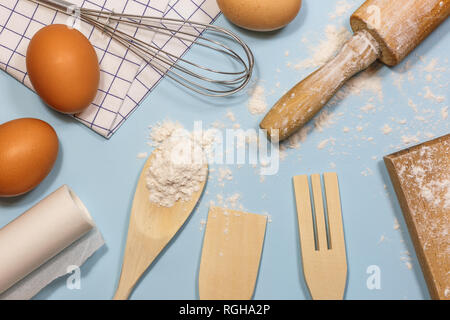 Des ingrédients et des ustensiles de cuisine pour la cuisson des gâteaux. Des ustensiles de cuisine, la farine et les oeufs sur un fond clair, vue du dessus. Banque D'Images