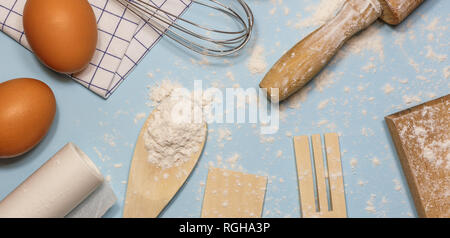 Des ingrédients et des ustensiles de cuisine pour la cuisson des gâteaux. Des ustensiles de cuisine, la farine et les oeufs sur un fond clair, vue du dessus. Banque D'Images