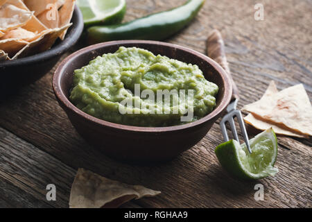 Dip guacamole frais avec le jus de lime dans un bol en céramique sur table rustique en bois, style mexicain traditionnel, sauce à l'avocat, snack-végétalienne saine Banque D'Images