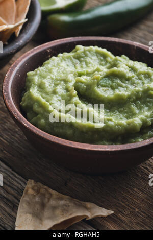 Dip guacamole frais avec le jus de lime dans un bol en céramique sur table rustique en bois, style mexicain traditionnel, sauce à l'avocat, snack-végétalienne saine Banque D'Images