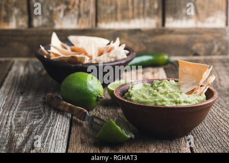 Dip guacamole frais avec le jus de lime dans un bol en céramique sur table rustique en bois, style mexicain traditionnel, sauce à l'avocat, snack-végétalienne saine Banque D'Images