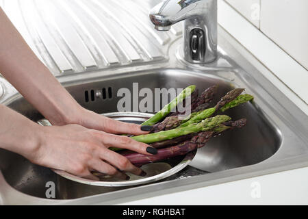 Laver les asperges vertes et violettes en pot métal dans la cuisine Banque D'Images