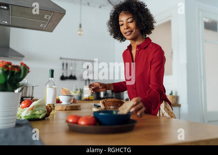 Femme debout dans la cuisine, le pain en tranches Banque D'Images