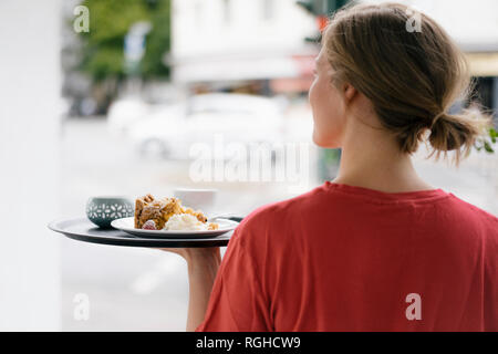 Jeune femme viewof arrière servant du café et des gâteaux dans un café Banque D'Images