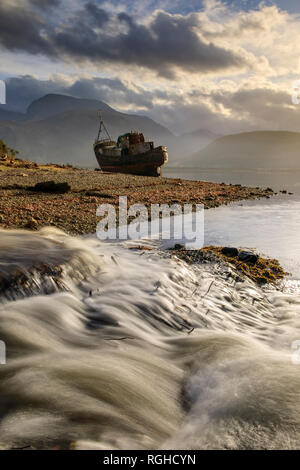 Le Ben Nevis capturées à partir de Corpach dans avec une cascade et bateau abandonné au premier plan. Banque D'Images