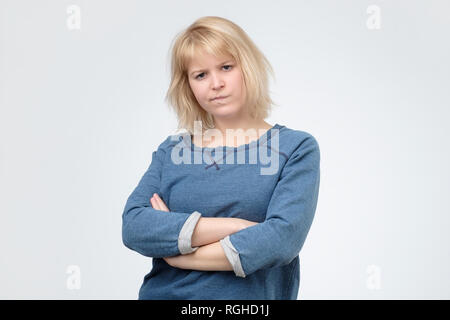 Contrarié insatisfait blonde woman standing with arms folded Banque D'Images