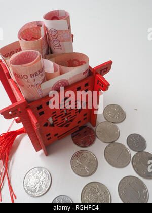 Pavillon chinois miniature en rouge lumineux rempli de 100 billets et renminbi chinois entouré de 1 yuan coins Banque D'Images