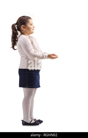 Profil de pleine longueur tourné d'une petite fille faisant des gestes avec ses mains et attendre de recevoir quelque chose d'isolé sur fond blanc Banque D'Images