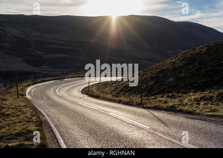 Vue panoramique sur une route de campagne sinueuse, l'A93, à travers le parc national de Cairngorms, Écosse, Royaume-Uni, le matin ensoleillé de l'hiver Banque D'Images