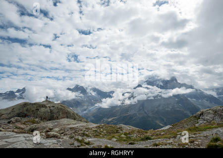 Une personne se tient sur un promontoire rocheux au dessus de la vallée de Chamonix, vue vers le massif du Mont Blanc. Cloudscape strié de la solitude et de l'hauteur souligne Banque D'Images