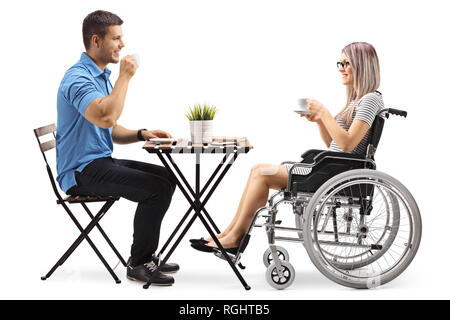 Jeune homme de boire du café avec une femme handicapée dans un fauteuil roulant isolé sur fond blanc Banque D'Images