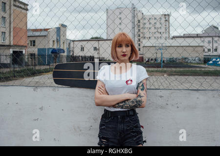 Jeune femme cool avec carver skateboard standing outdoors Banque D'Images