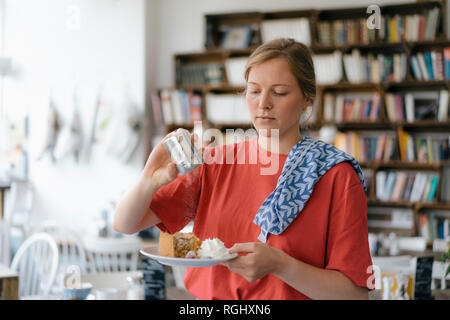 Jeune femme avec une assiette de gâteau dans un café Banque D'Images