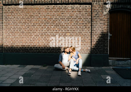 Pays-bas, Maastricht, jeune couple ayant une pause dans la ville assis sur un trottoir Banque D'Images