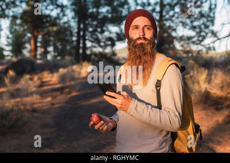 États-unis d'Amérique, Californie, barbu avec un téléphone mobile et apple dans une forêt près de Lassen Volcanic National Park Banque D'Images