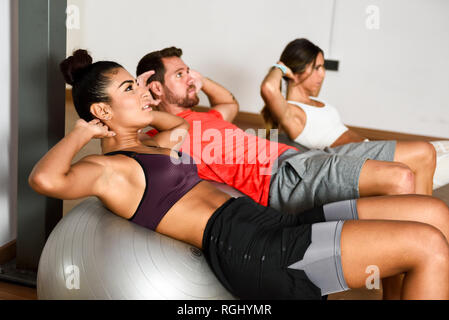 Les jeunes faisant des craquements sur un ballon de gymnastique Banque D'Images