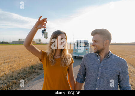 Jeune couple avec clé de voiture sur un chemin de terre à camper van in rural landscape Banque D'Images