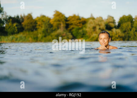 Portrait of smiling woman swimming in a lake Banque D'Images