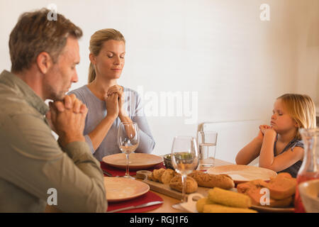 Prier en famille avant de dîner sur la table à manger à la maison Banque D'Images