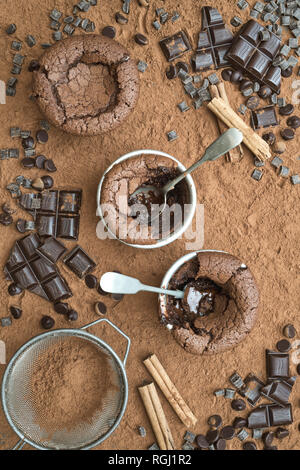 Fondant au chocolat au lait fait maison entourée par la poudre de cacao et le chocolat noir en morceaux Banque D'Images