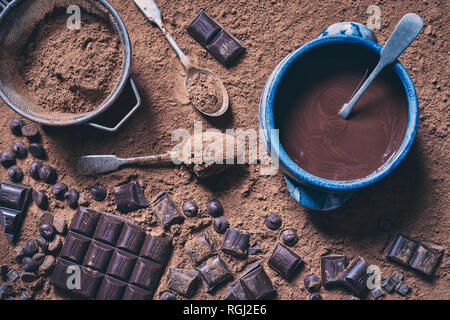 Le chocolat fondu dans un bol entouré de morceaux de chocolat, vieux métal cuillères à café et cacao en poudre Banque D'Images