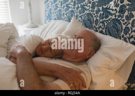 Senior couple embracing ensemble tout en dormant dans la chambre Banque D'Images